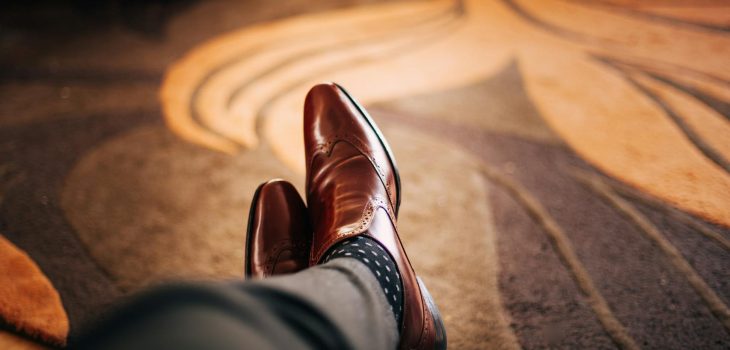 shallow focus photography of person wearing brown leather dress shoes
