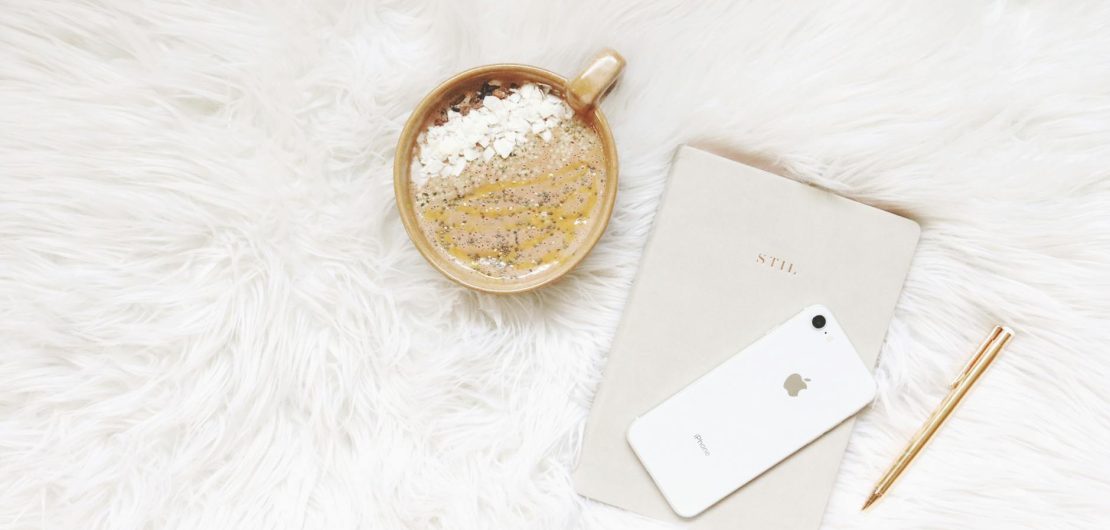 white iphone gold colored pen and round gold colored cup