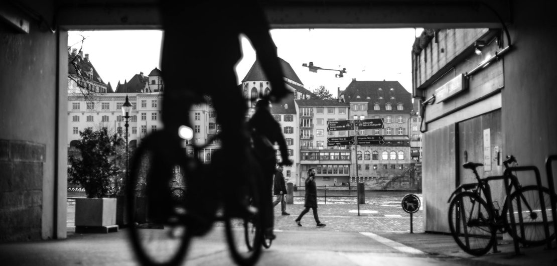 man riding a bike on a street in black and white