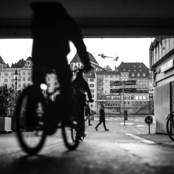 man riding a bike on a street in black and white